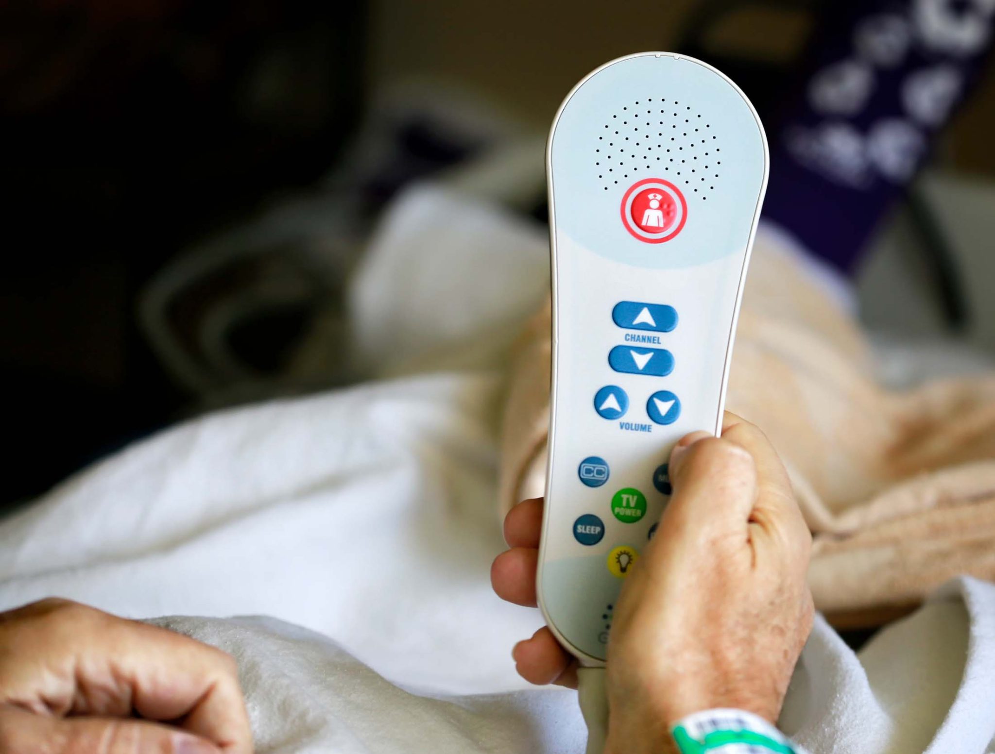 Patient holding TV remote with nurse call button